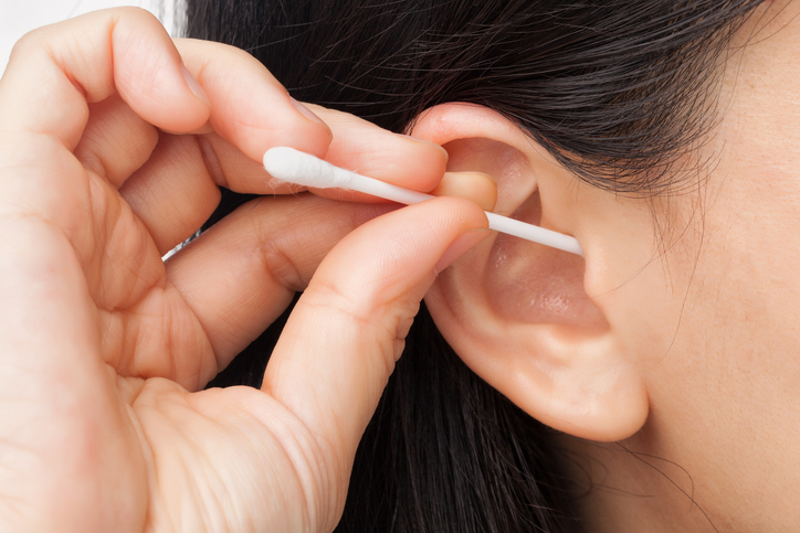 una mujer se limpia la oreja con un bastoncillo de algodón